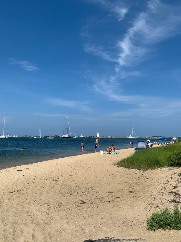People enjoying the beach with boats in the water