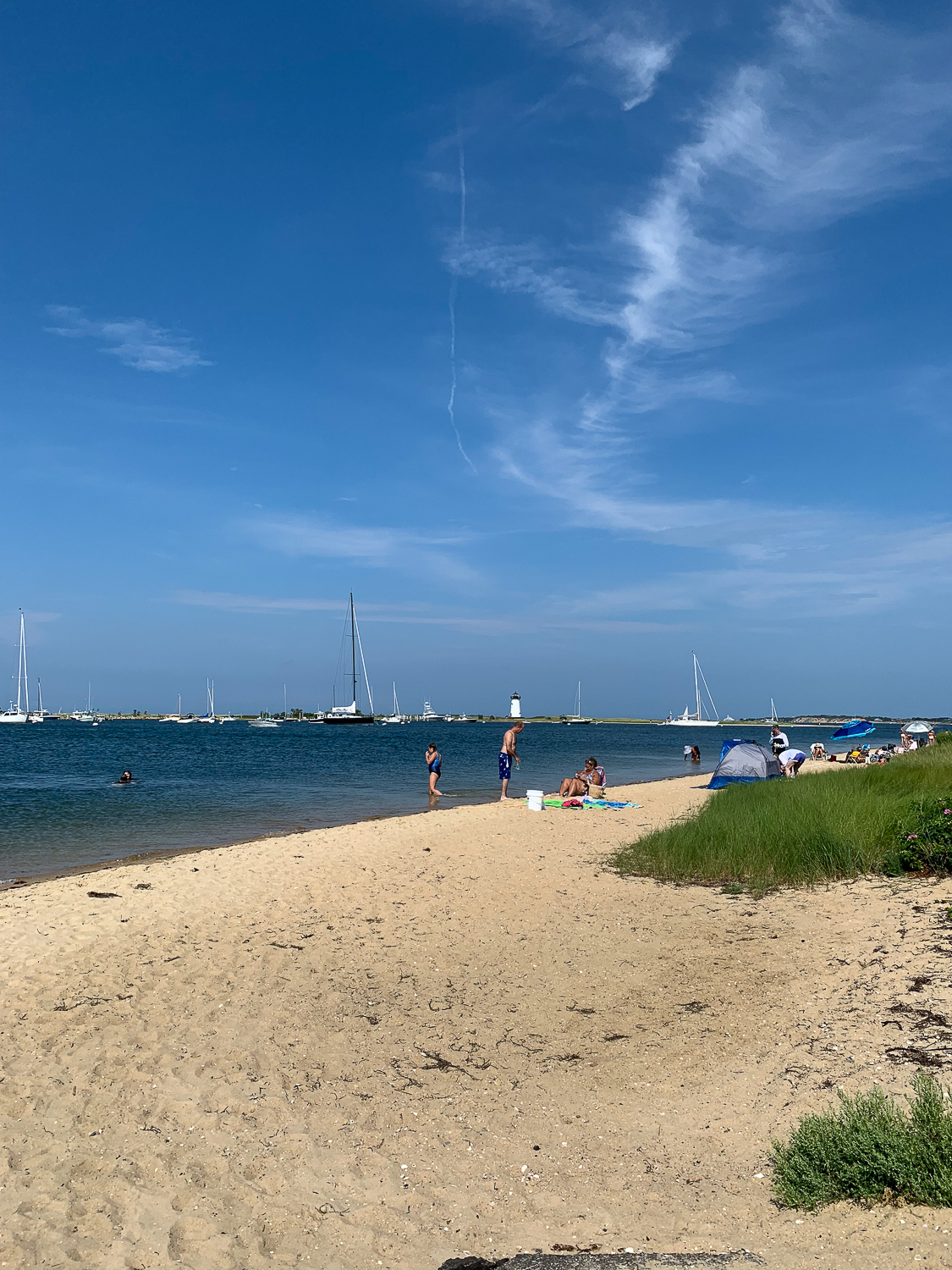 People enjoying the beach with boats in the water